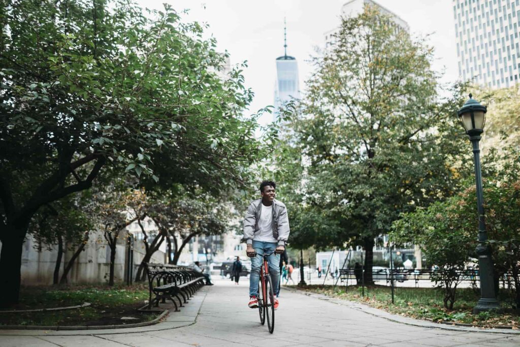Man biking on a large sidewalk in the city.