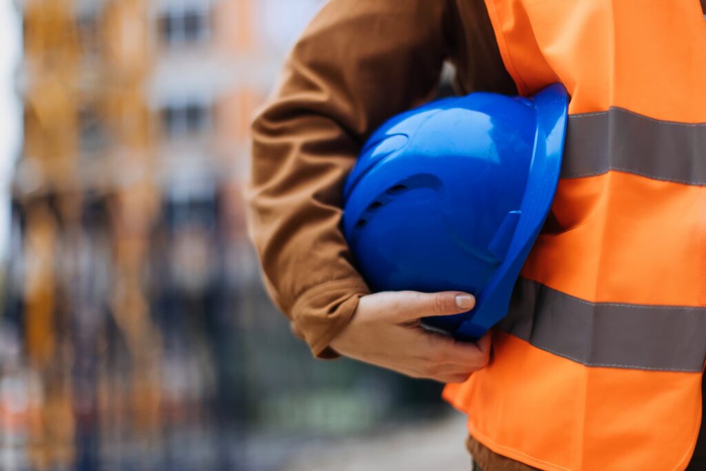 Construction worker holding a blue hard hat.