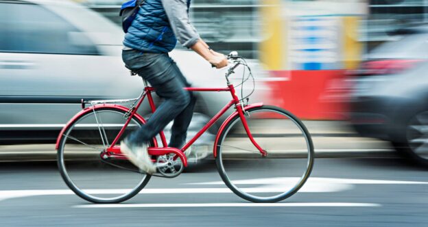 A passenger on a bike passing cars