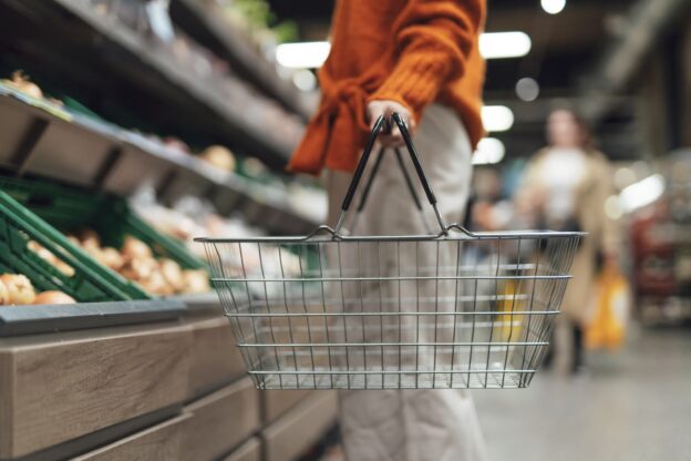 Person carrying grocery basket in store