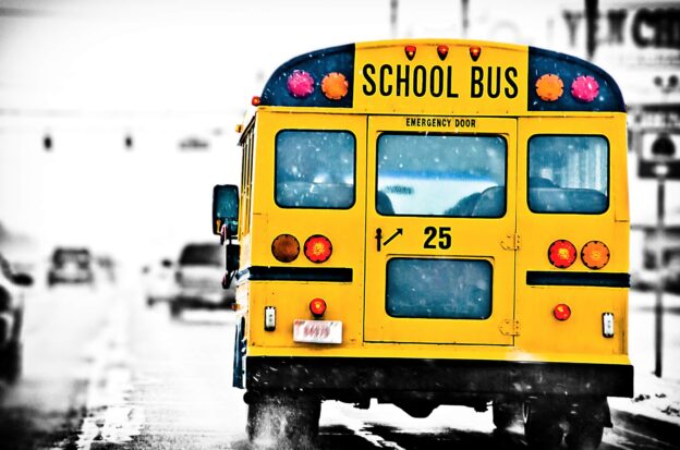 School Bus Driving Down a Street on a Cold and Snowy Day
