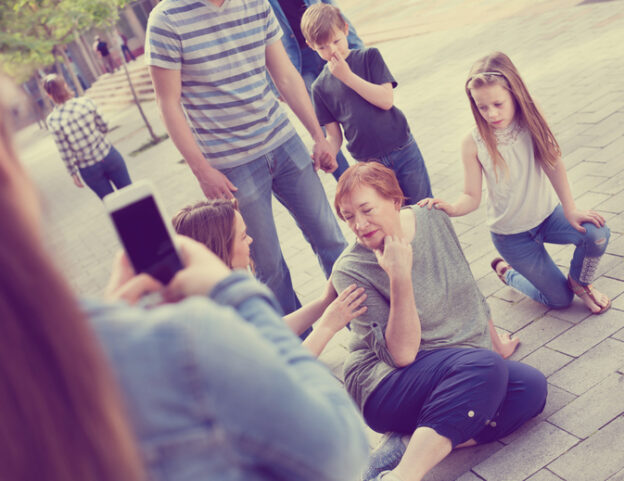 Relatives standing near their grandmother who fell on a sidewalk